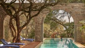 In einem Swimmingpool eines Hotels streichelt eine Frau eine Giraffe, die vor dem Pool steht. 