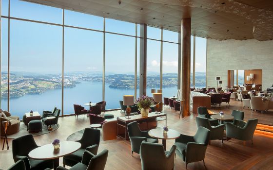 In einem Restaurant besteht eine Wand aus bodentiefen Fenstern mit Blick auf einen See. 