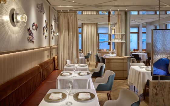 Stilvoller, menschenleerer Speiseraum eines Restaurants mit eingedeckten Tischen und hellen Designelementen.