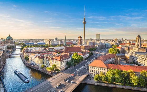 Luftaufnahme zeigt Berlin Mitte und den Alexanderplatz, über den Häusern ragt der Fernsehturm empor und an der Seite fliesst der Fluss Spree. 