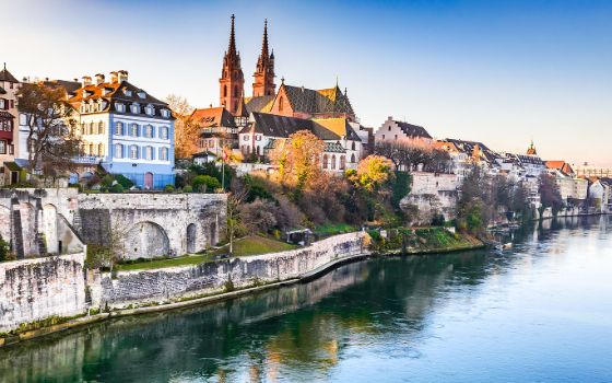 Basler Stadtpanorama mit historischen Häusern und Kirche am Fluss.