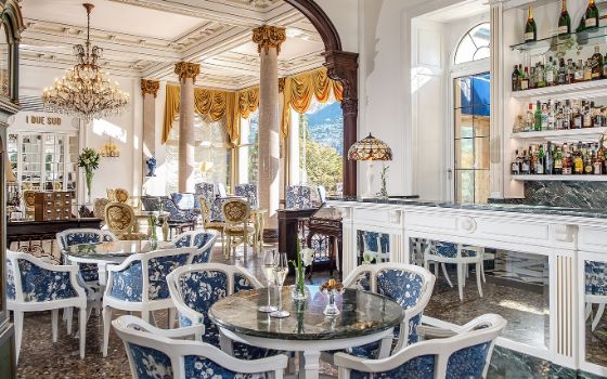 Opulent eingerichteter, heller Speisesaal mit Bar in einer barocken Villa mit Stuckdecke und Kronleuchter. 