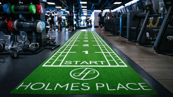 Eine grüne Matte mit Metermarkierungen und dem Aufdruck Holmes Place in einem Fitnessstudio. 