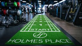 Eine grüne Matte mit Metermarkierungen und dem Aufdruck Holmes Place in einem Fitnessstudio. 