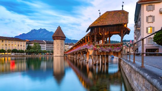 Kapellbrücke und Wasserturm in Luzern bei Sonnenuntergang, Wahrzeichen der Stadt mit Blick auf den Pilatus, exklusives Reiseziel mit American Express Vorteilen.