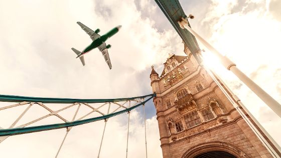 Aufsicht zur London Tower Bridge, im Himmel über der Brücke fliegt ein Flugzeug.