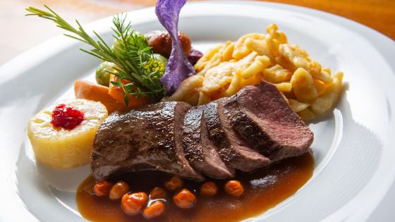 Nahaufnahme eines edel angerichteten Fleischgerichtes mit Beilagen auf einem weissen Teller.