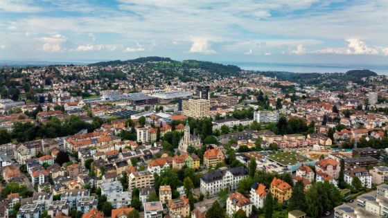 Panoramaaufnahme von St. Gallen mit Blick über die Stadt, Wohnviertel, Kirchen und bis zum Bodensee im Hintergrund.