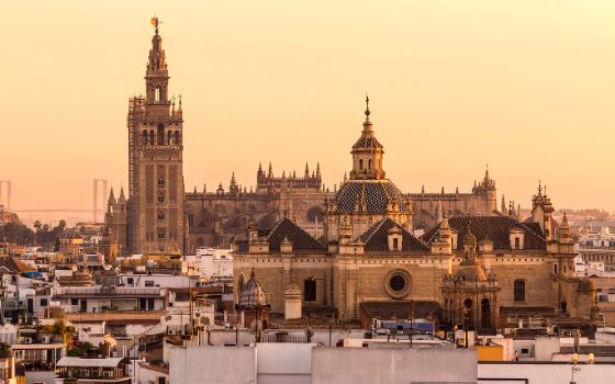 Blick auf die Kathedrale von Sevilla mit Giralda-Turm bei Sonnenuntergang über den Dächern der Altstadt