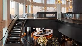 In einem lichtdurchfluteten Raum führt eine Treppe von einem Restaurant in die obere Etage.