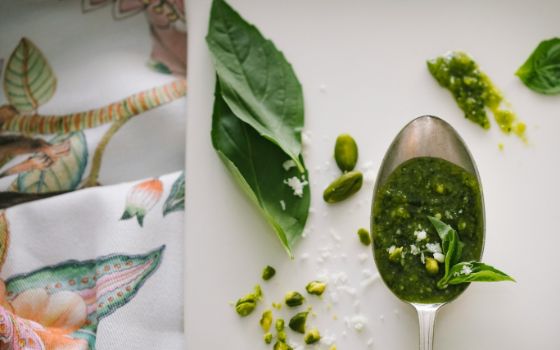 Ein Löffel frisches Pesto mit Basilikum und Pistazien auf einem hellen Untergrund