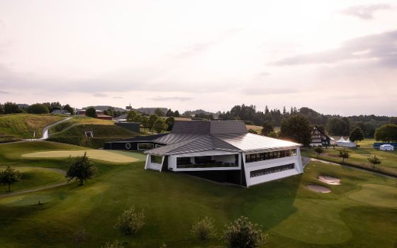 Auf einem Golfplatz stehen Gebäude in futuristischer Architektur. 