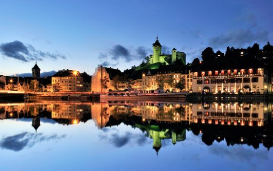 Beleuchtete Altstadt von Schaffhausen mit Munot-Festung bei Nacht, Spiegelung im Rhein.
