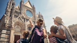 Mutter und Kinder betrachten die gotische Kathedrale von Siena in Italien; eines der Kinder zeigt auf die Fassade.