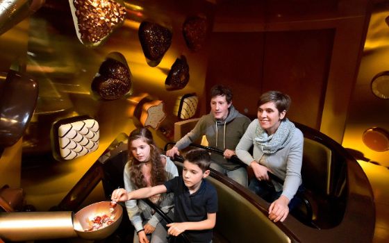 Familie in interaktiver Ausstellung mit Pralinenmotiven im Swiss Chocolate Adventure im Verkehrshaus Luzern.