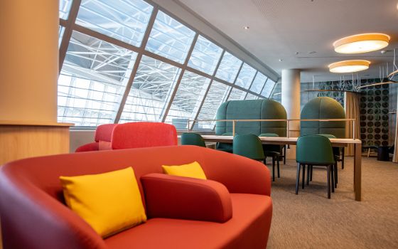 Ein elegantes rotes Sofa mit gelben Kissen steht in der Marhaba Lounge im Flughafen in Zürich.