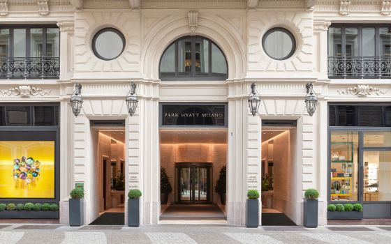 Historische Hausfassade mit elegantem Eingangsbereich zum Hotel Park Hyatt Milano und Geschäften. 