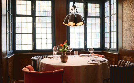 Ein eleganter Tisch steht in einer gemütlichen Loggia mit hellen Fenstern und ist gedeckt mit hochwertigen Gläsern und Tellern.