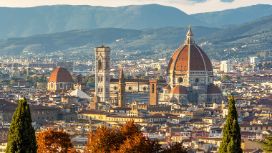 Blick auf den Dom von Florenz mit Kuppel und Campanile im warmen Herbstlicht, eingerahmt von Zypressen und Herbstlaub