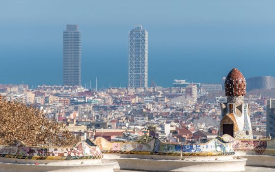 Blick vom Park Güell über die Dächer Barcelonas mit den beiden markanten Hochhäusern am Meer im Hintergrund.