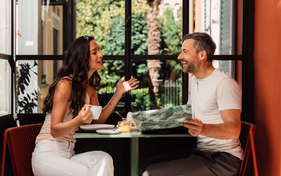 Paar geniesst entspannten Café-Besuch, sitzt an einem Tisch bei Kaffee und Croissants, American Express Vorteile erleben.