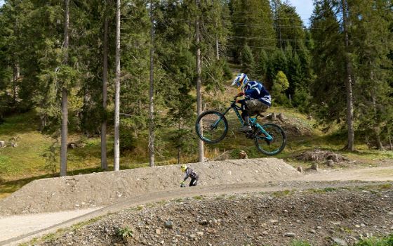 Ein Mountainbiker fährt über einen Hügel in einer Fahrradstrecke.