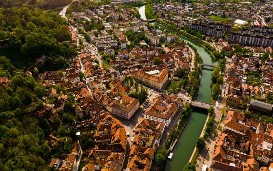 Luftaufnahme von Ljubljana in Slowenien mit Altstadt, Fluss Ljubljanica und grünen Hügeln im Hintergrund.