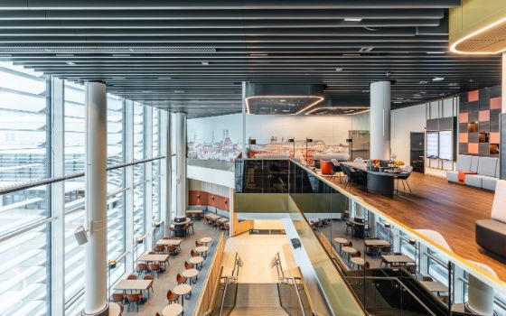 Zweistöckige Lounge am Airport München mit Treppe, Tisch- und Stuhlgruppen und grosser Fensterfront.