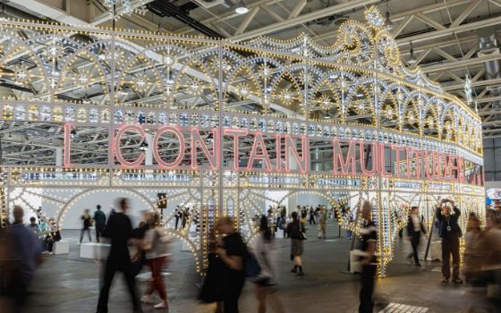 Personen bewegen sich um eine raumfüllende skulpturale Lichtinstallation in einer Messehalle. 