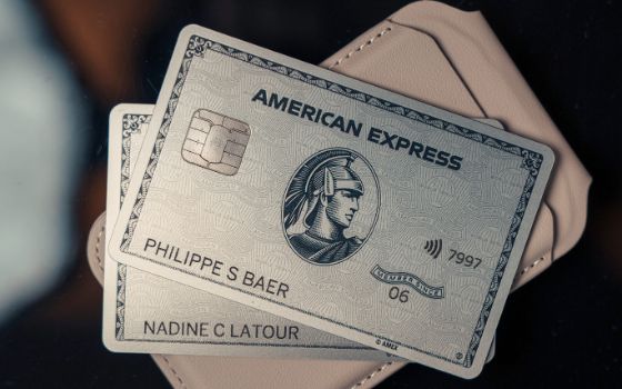 Zwei Kreditkarten von American Express liegen auf einem rosafarbenen Portemonnaie.