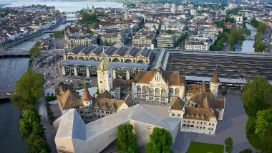 Das Landesmuseum Zürich aus der Luft, das alte Gebäude besteht aus Türmen und verzierten Fenstern und ist direkt mit dem modernen Neubau verbunden, der eine zackige und längliche Form hat.