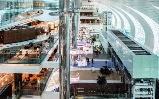 In einem mehrstöckigen Flughafengebäude stehen Sessel und Boutiquen. 