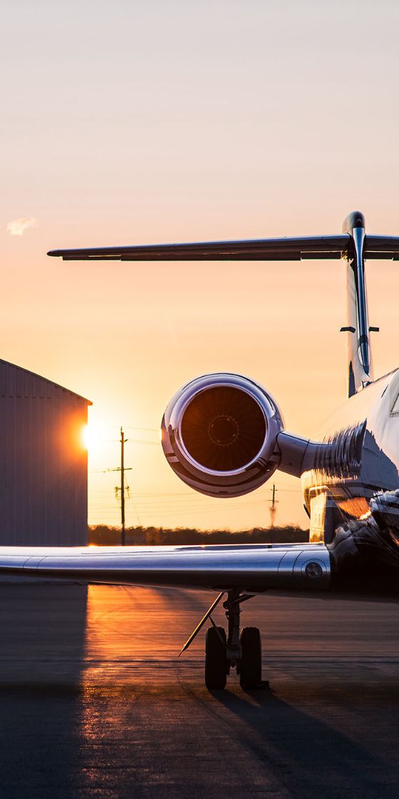 Ein Flugzeug steht im Sonnenuntergang auf einer Landebahn.