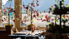 Vor einem Fenster steht ein gedeckter Tisch, auf den das Sonnenlicht fällt. 