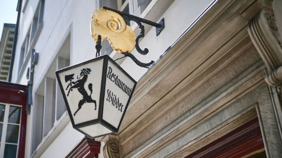 Aussenleuchte mit aufgedrucktem Widder-Wappen und Aufschrift «Restaurant Widder» über der Eingangstür eines historischen Hauses. 