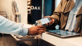 Eine Person hält ihre Smartwatch an ein Lesegerät zum bargeldlosen Bezahlen. 