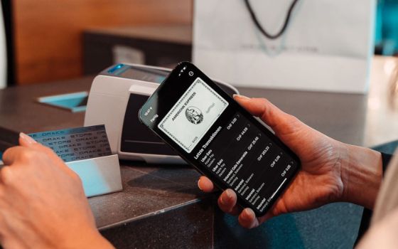 Mobile Payment mit einer American Express Platinum Card via Smartphone an einem Kartenlesegerät in einer Boutique