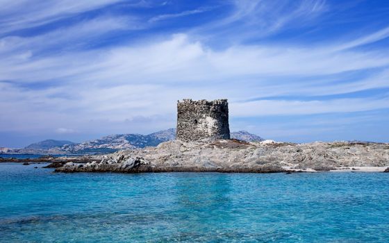 Mittelalterlicher Turm auf Felsen im türkisblauen Meer bei La Pelosa, einer der schönsten Strände im Norden von Sardinien.