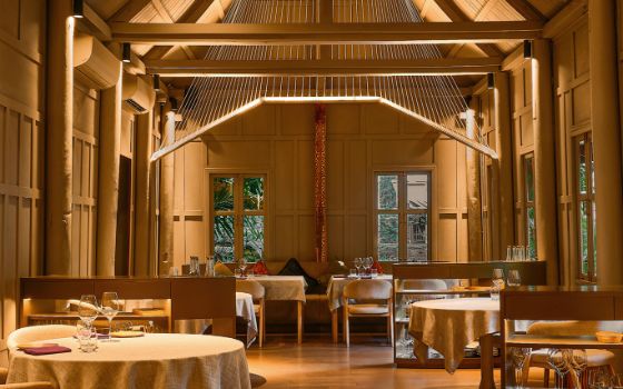 In einem Restaurant mit Holzwänden stehen gedeckte Tische, an der Decke hängt ein Holzobjekt als Dekoration.