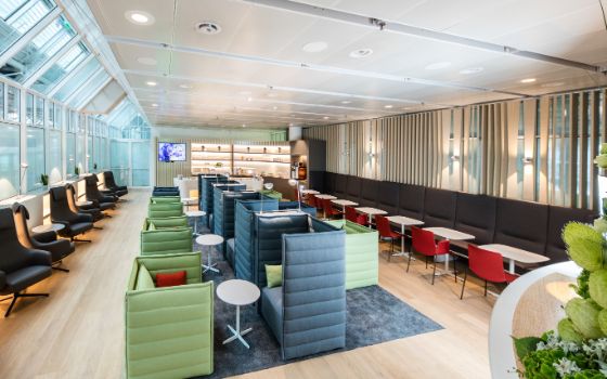 Weitwinkelaufnahme einer Lounge am Airport München mit Holzboden, Sitzgruppen mit Tischen, Sesseln und Sofas.