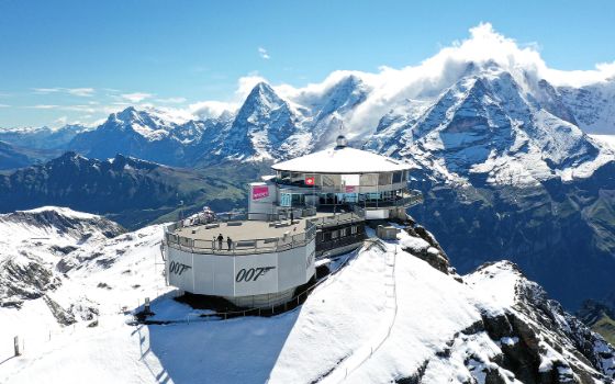 Auf einem hohen Berg steht ein eckiges Gebäude mit dem Schriftzug 007 am Geländer.