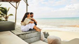 Paar sitzt entspannt auf einer Strandterrasse mit Blick auf das Meer
