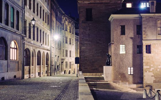Nächtliche Gasse in der Altstadt von Genf mit Pflastersteinen, historischen Fassaden und beleuchteten Fenstern.